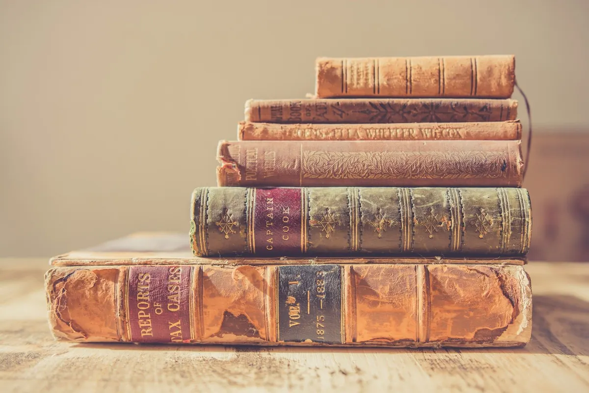 Stapel von Büchern mit Ledereinband auf hellem Holz