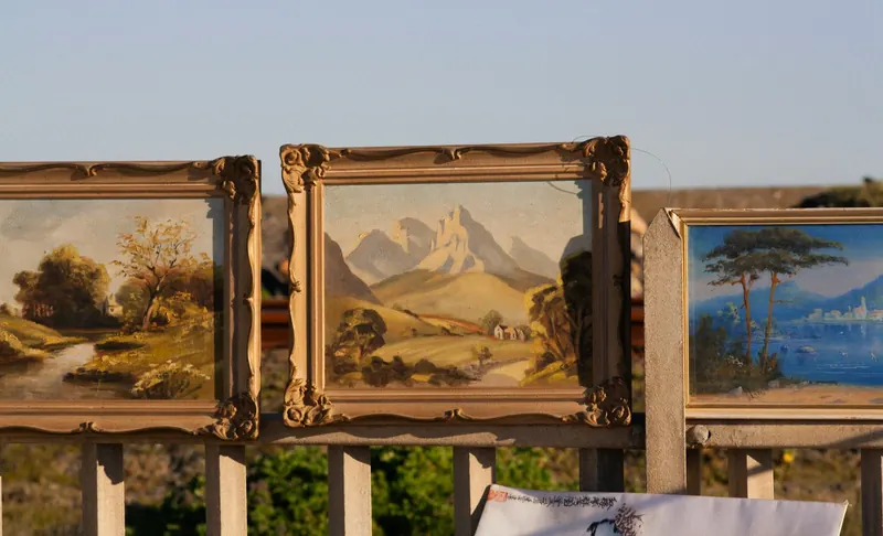 Trois paysages peints dans des cadres dorés sur une rambarde