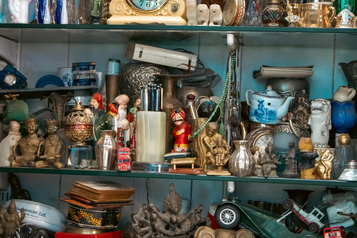 Étagère remplie de figurines, théière, petites voitures et laiton