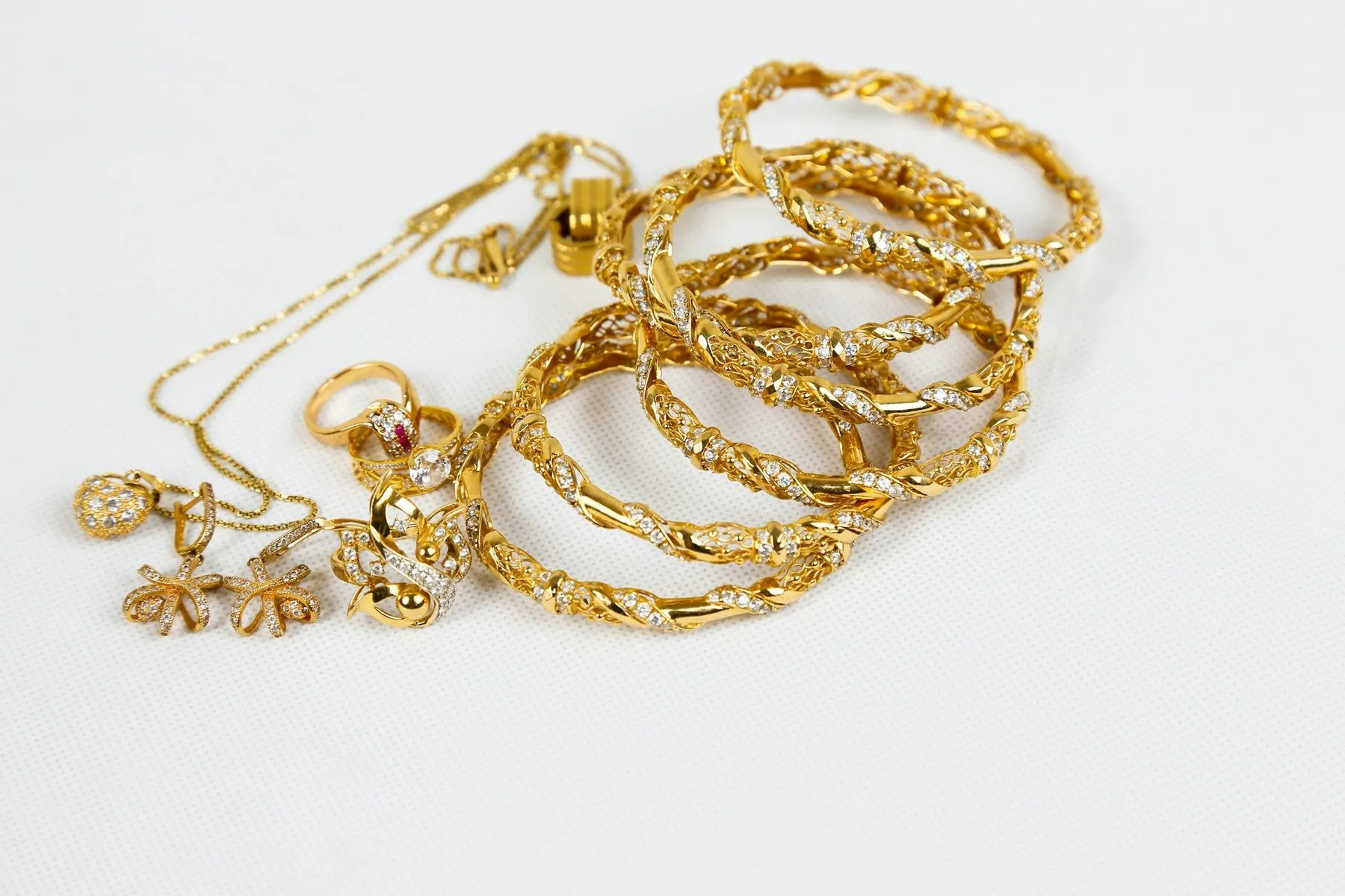 Bracelets, chaînes et bagues en or sur fond blanc