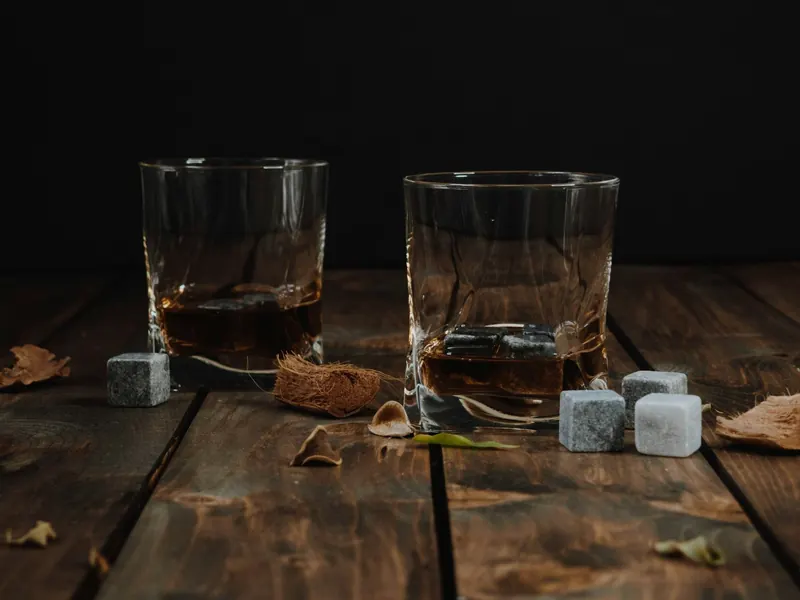 Deux verres à whisky avec des pierres à whisky sur une table en bois sombre